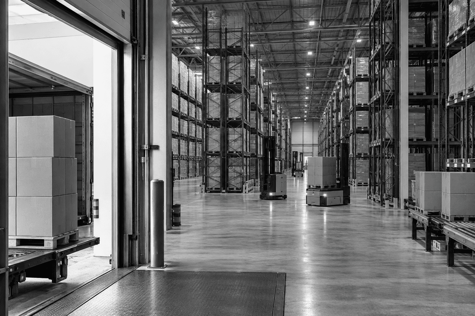Illustrative black-and-white photograph of warehouse aisles, pallet racking, and automated materials handling.
